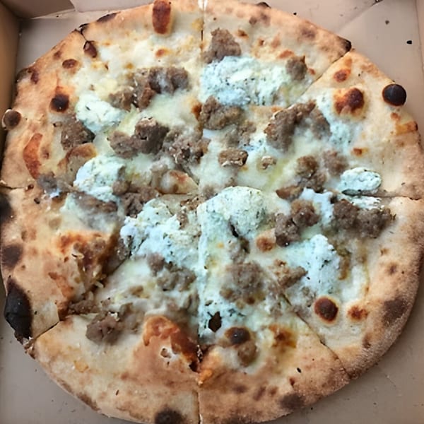 A CraveN Pizza with white sauce, crumbled sausage, and ricotta cheese in a delivery box.