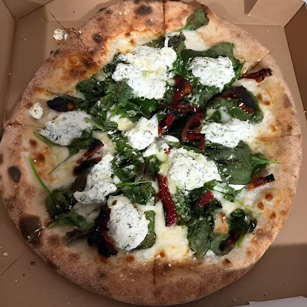 CraveN Pizza's whole pizza with arugula, ricotta cheese, and sun-dried tomatoes in a box.