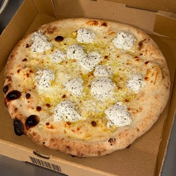 CraveN Pizza's white pizza with dollops of ricotta cheese and a golden crust in a box.