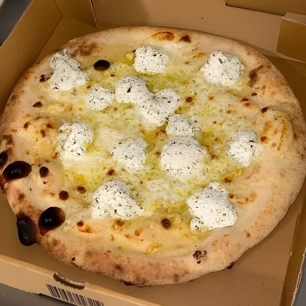 A CraveN Pizza white pizza with dollops of ricotta cheese and a golden crust in a delivery box.